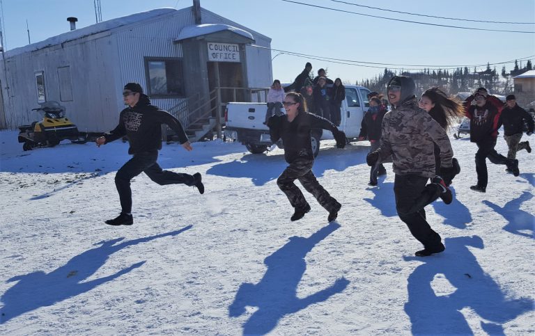 Runners race down a snowy street in Arctic Village during the spring carnival