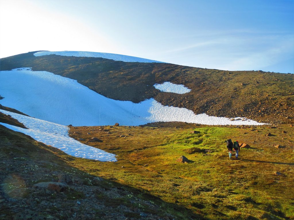 snow patch and Alaska mountain landscape with hikers