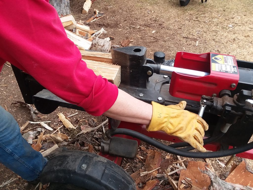 A close up of an engine-powered wood splitter being used