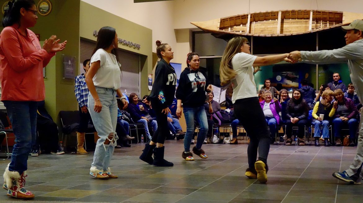several people square dance solo while one couple dances together during the Gwich'in Fiddle Dance