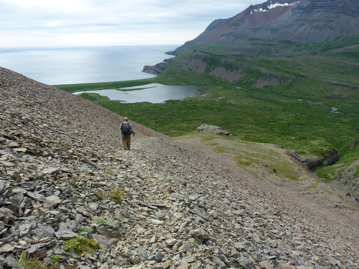 Hiker on a rocky skree slope by coast on Kanatak Trail