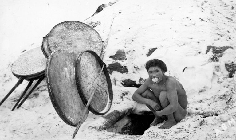 yup'ik man squatting outside steambath