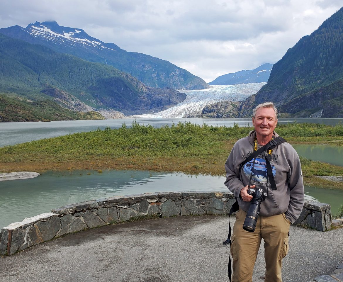 Nick Jans holding a camera and standing near Mendenhall Glacier