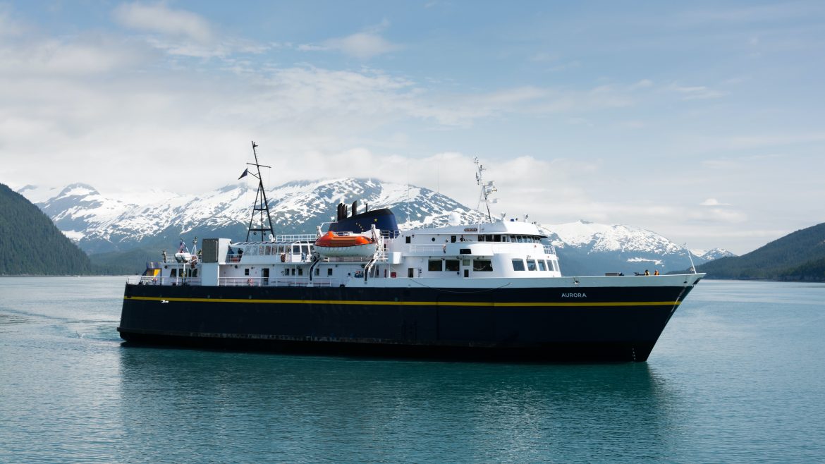 Alaska state ferry on calm blue water with snowy mountains behind