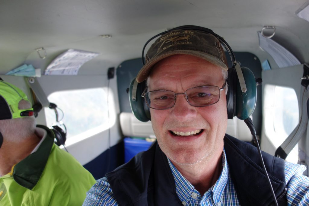 Scott McMurren in a small plane wearing headgear and smiling