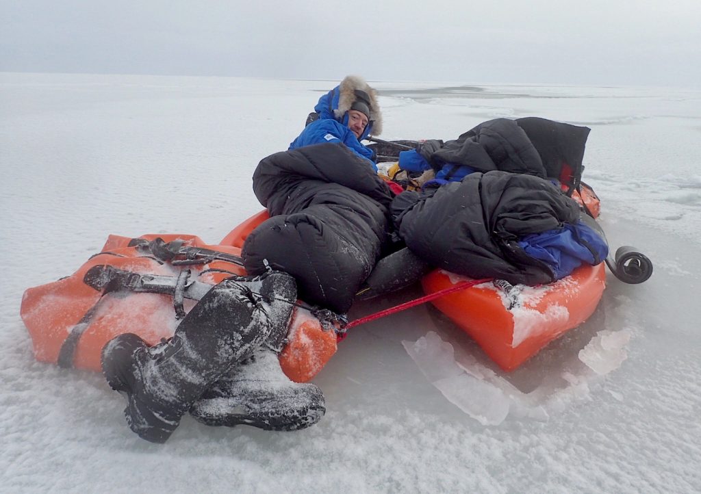 Men shelter on kayak platform over frozen sea ice