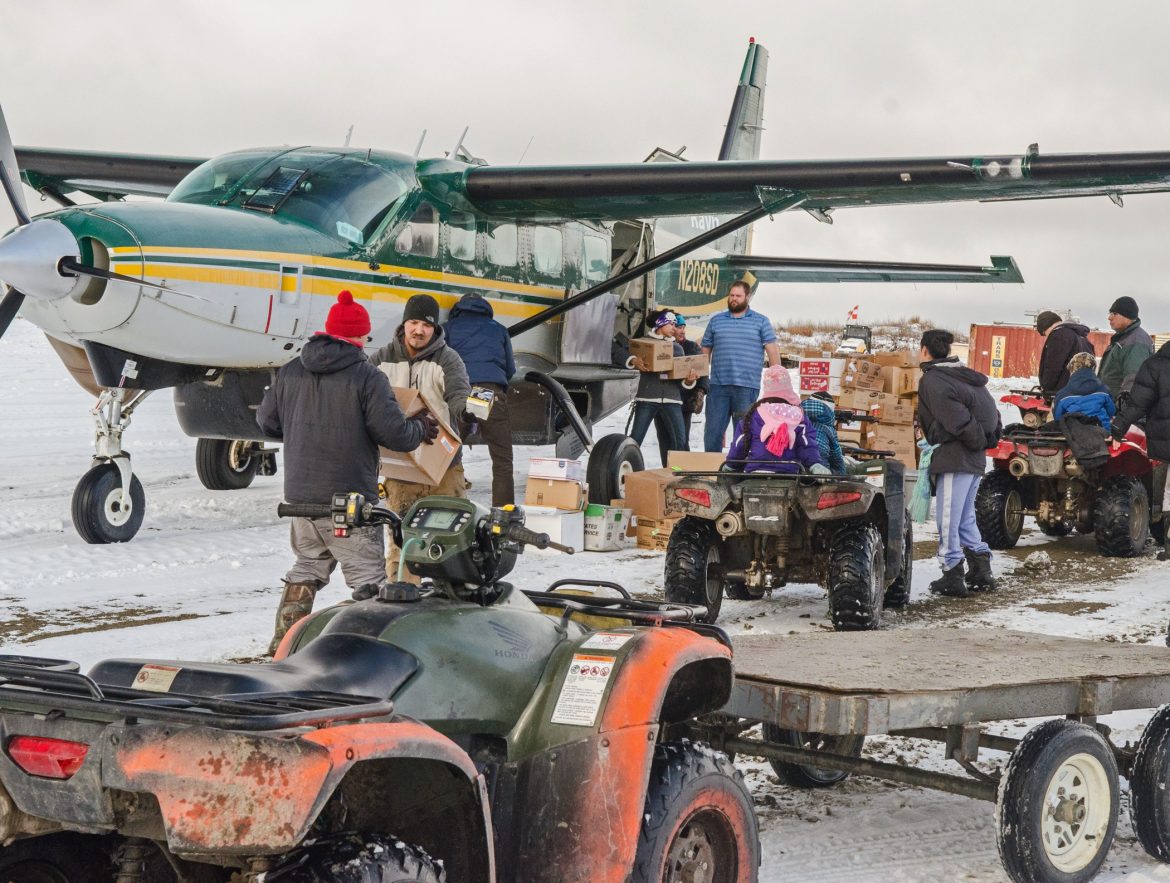 People and ATVs father by a plane on a snowy day