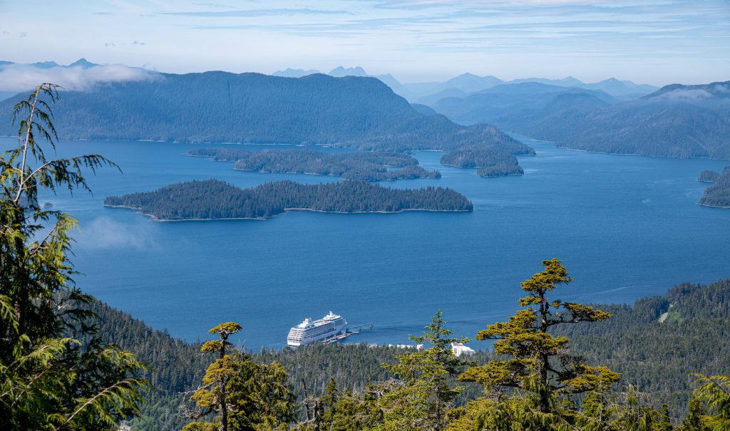 Cruise ship docked along forest coast. View of Inside Passage waters and islands.