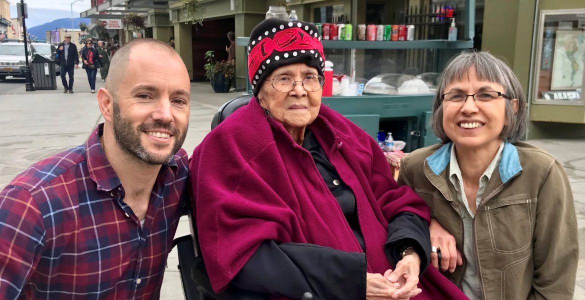 Man and woman around an elderly native alaskan storyteller