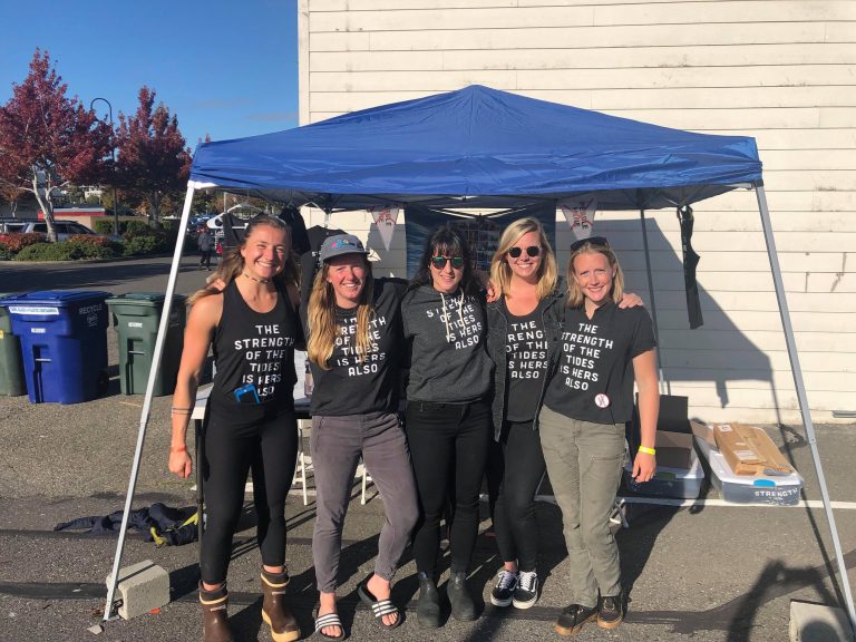 Women wearing Strength of the Tides tshirts by a tent