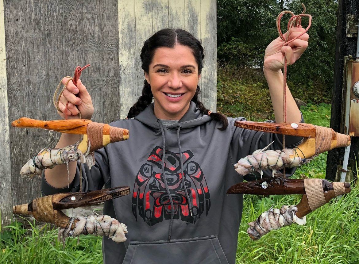 Heather Douville holds up four V-shaped wooden halibut hooks with octopus wrapped around one arm