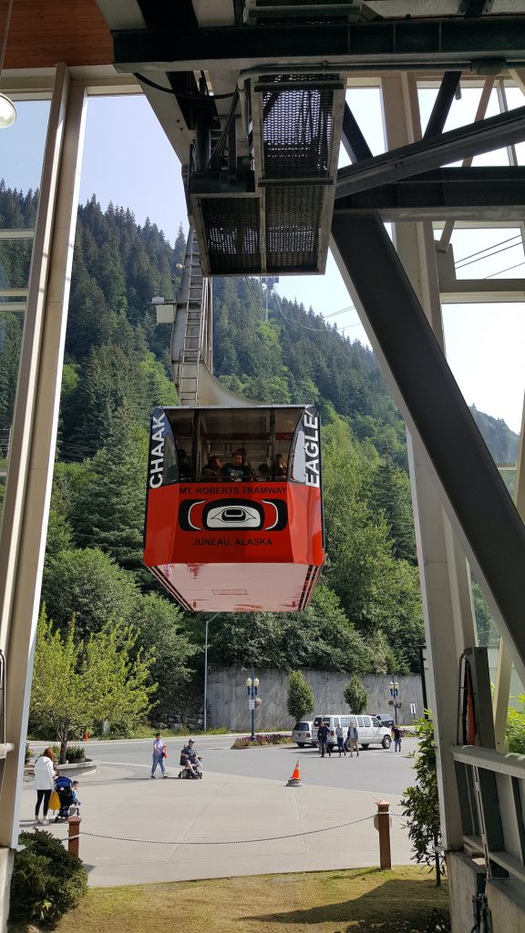 Image of red tram departing station and heading up mountain