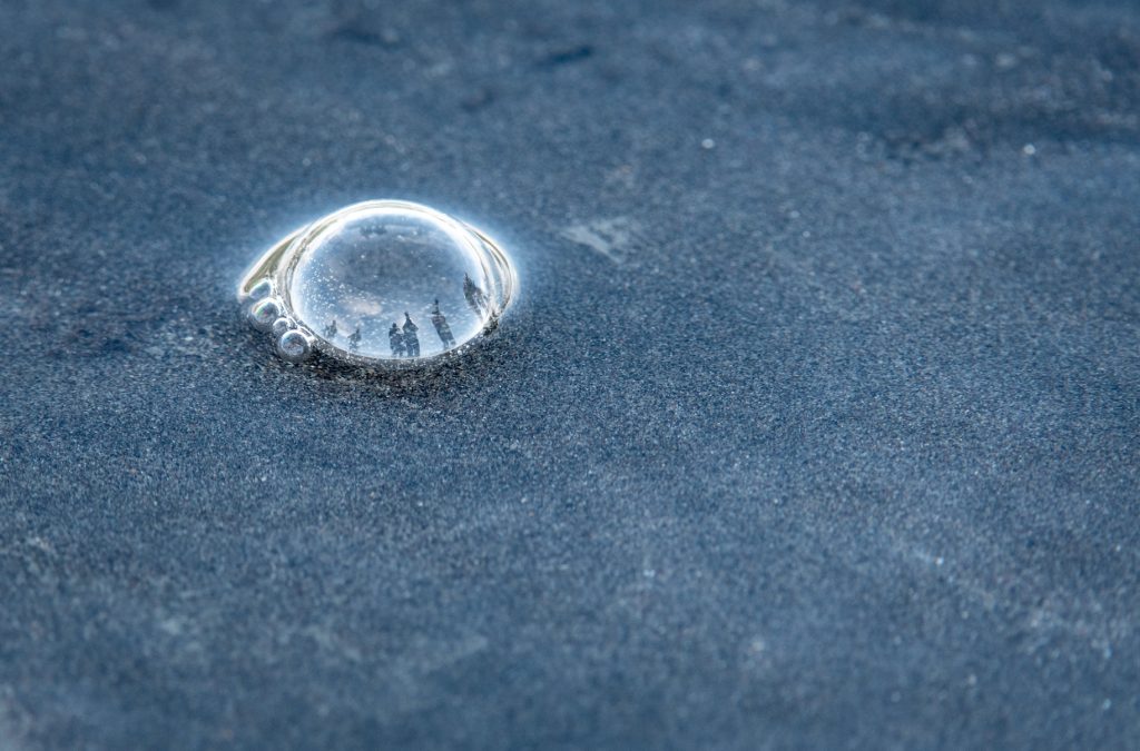 Small bubble on sand with tiny reflections in dome of photographers and upside down bears