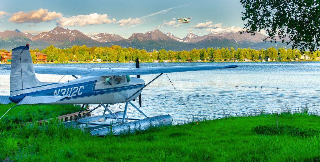 One plane in slip while other takes off at Lake Hood in Anchorage