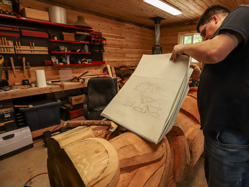 Tsimshian artist David R. Boxley flipping through a pad of paper with sketches on the pages