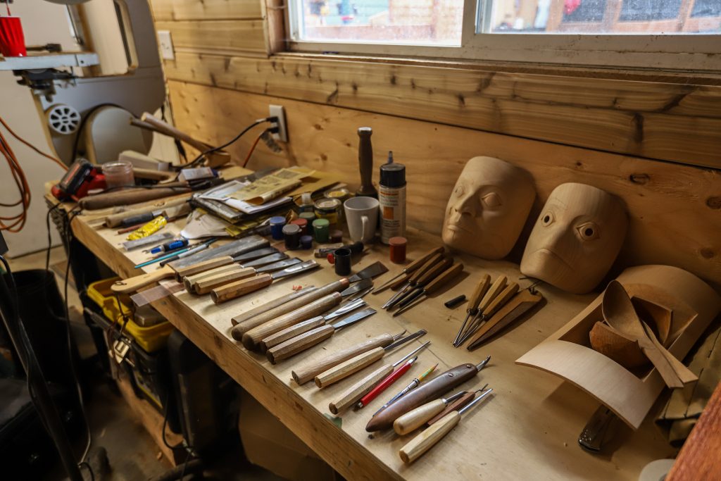 tools and some masks sitting on a wooden shelf
