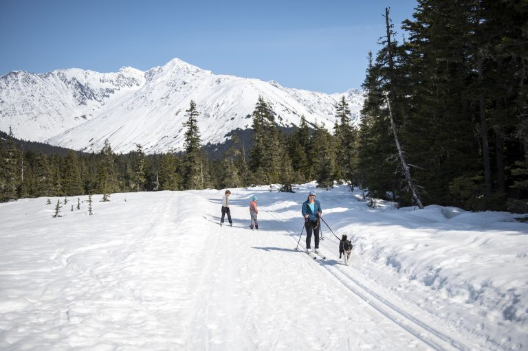 A family and dog ski along a Nordic ski trail in Girdwood.