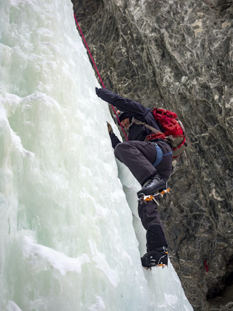 An ice climber scales a frozen sheet of ice