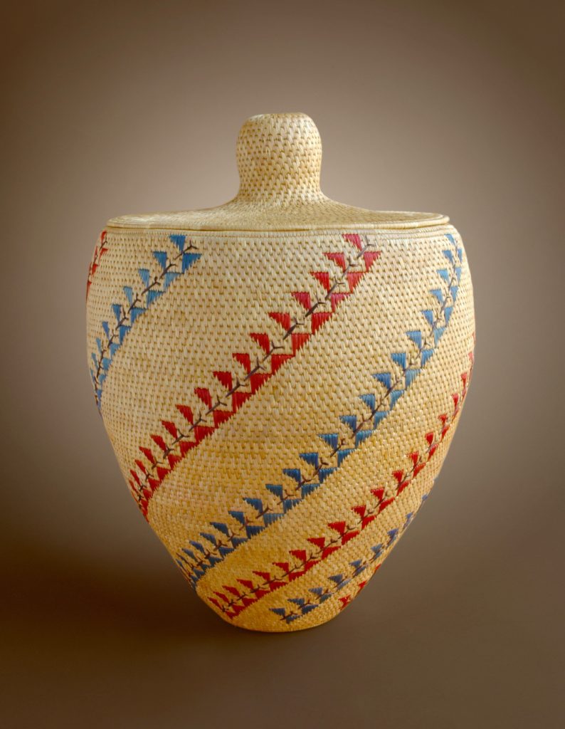 Grass basket with blue and red patterns woven in.