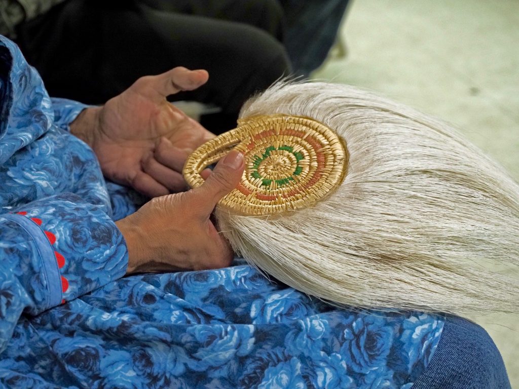 photo close on a woman's hands holding a woven circle with reindeer hair flowing from one side of the circle.