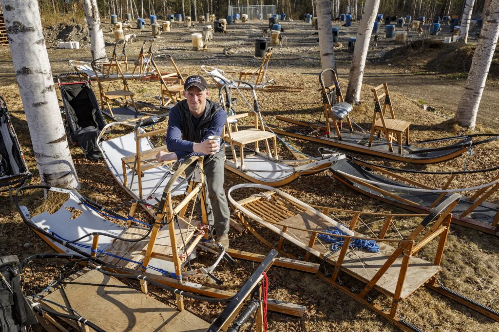 Iditarod champion Dallas Seavey puts leg up on a sled at his kennel during summer.