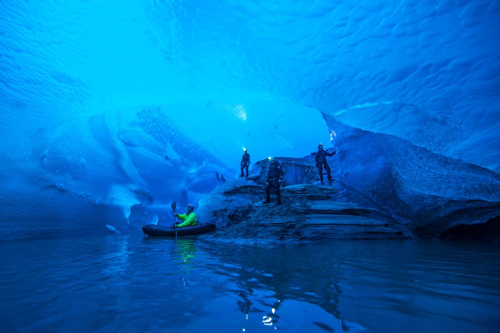People stand in an ice cave with water