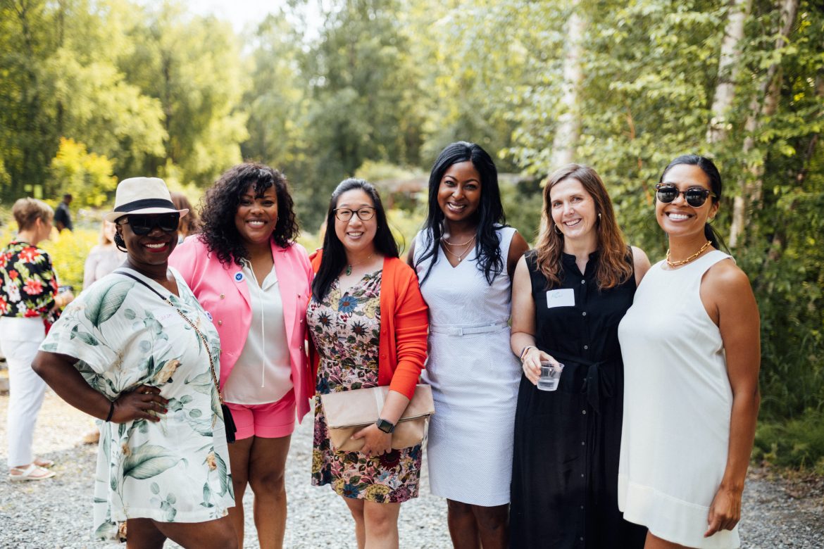 Group of women dressed in professional summer clothes pose for a picture