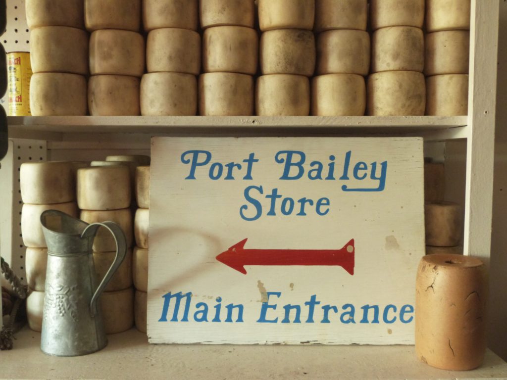 A sign for Port Bailey Store with arrow pointing to main entrance. Sits against stacks of corks