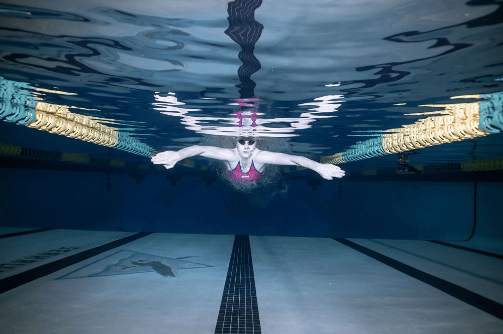 Underwater shot of Lydia Jacoby swimming. Arms out wide as if mid-breaststroke, she's in the center of a swim lane.