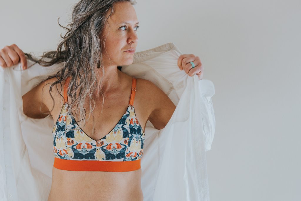 a middle-aged woman models a Swoop bra with a bright, colorful pattern