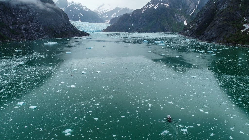 A fjord is spotted with ice. At the far end is a glacier