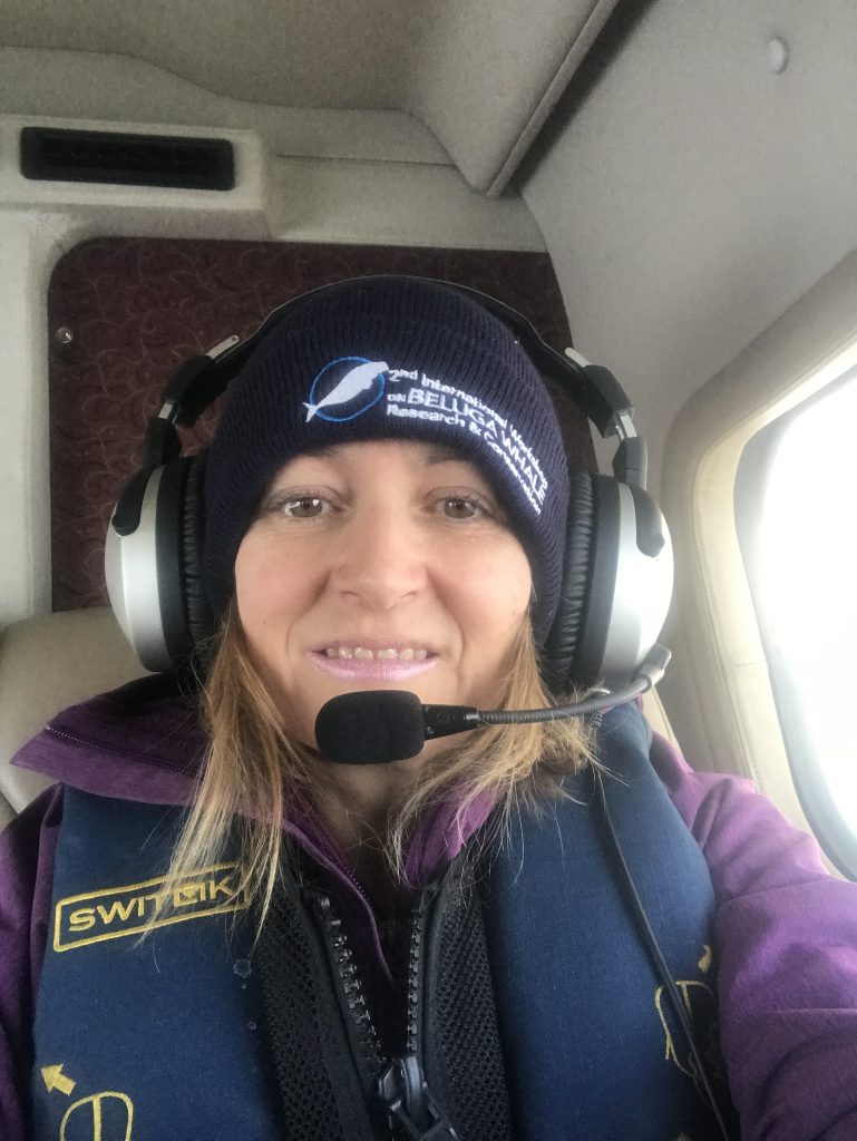 Verena Gill wearing a headset and sitting by a window on a small plane