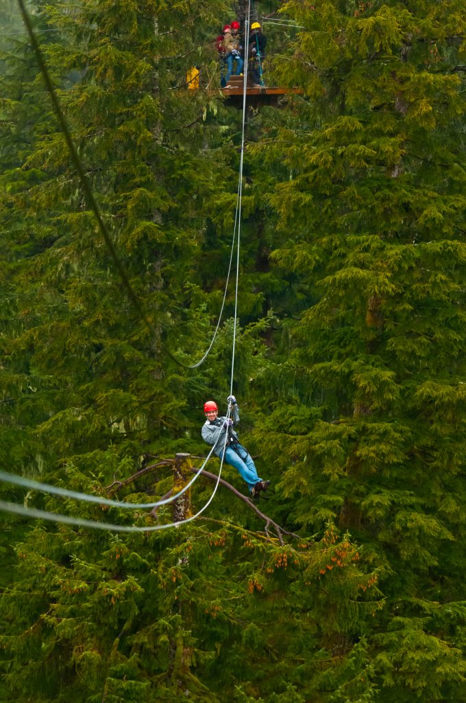 Person smiling as they ride a zipline through lush forest