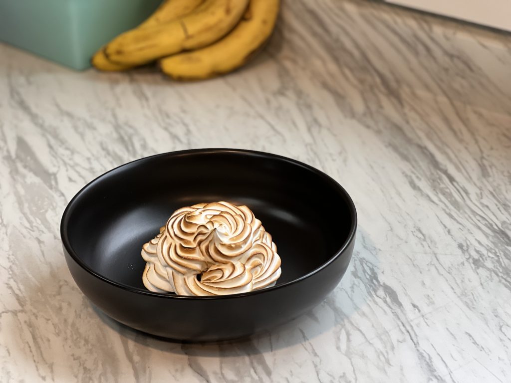 Baked Alaska in a black dish on a counter.